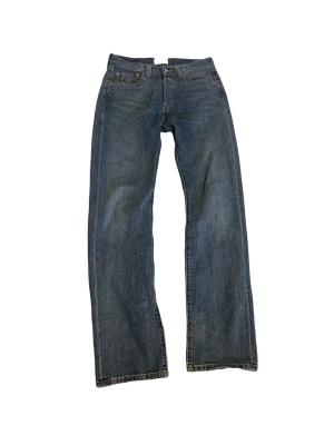 Blå raka jeans från Levi's - Klassiska blå jeans från Levi's med rak passform och fem fickor. Jeansen har en tidlös tvätt och är gjorda i slitstarkt denimtyg. Perfekta för dig som gillar en avslappnad och enkel stil.