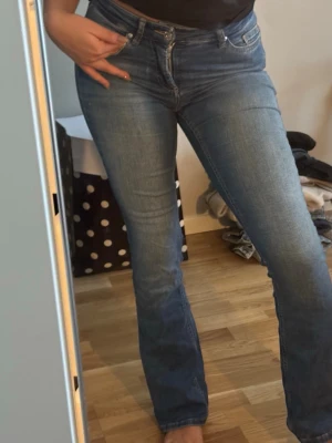 Blå bootcut jeans från ONLY - Säljer ett par klassiska blå midweist bootcut jeans från ONLY  som har femficksmodell. Dessa kommer inte till användning längre då dem blivit för små. Jeansen har en snygg tvätt och sitter bra över höften och låren innan de blir vidare nertill. Perfekta till sneakers eller boots.