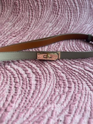 Grått skärp  - . Skärpet har en slät yta och insidan är brun. Perfekt accessoar för att lyfta din outfit med en lyxig touch.