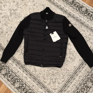 Moncler Cardigan - En svart moncler cardigan. Säljer den eftersom storleken är ganska liten för mig. Litet hål i fickan. Storlek m men passar även S. Hör av er om ni är intresserad😊