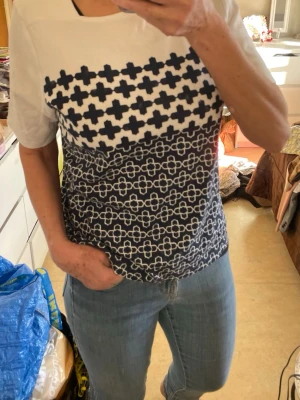 Croft&Barrow  t-shirt - Säljer Croft&Barrow  t-shirt vit t- med mörkblå geometriskt mönster framtill. T-shirten har korta ärmar och en rak passform. Materialet är  bomull och den är perfekt för dig som gillar grafiska prints.det står  storlek L på men jag tycker den är som en medium 