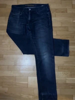 Mörkblå jeans från American Eagle - Ett par riktigt schyssta America Eagle jeans med en liten slitning på knät och lite mer vintage wash blå, Knappt använda. För bättre bilder och/eller andra frågor så är det bara att skriva, pris kan även diskuteras!😁✌🏼