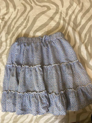 Blommig volangkjol i blått - Blommig kjol i storlek S. Kjolen passar även om man har storlek M och kanske XS. Säljer pga att den inte används. Kjolen har använts ca 3 ggr. Etiketten är bortriven men märket var Gina Tricot. Pris kan diskuteras💗
