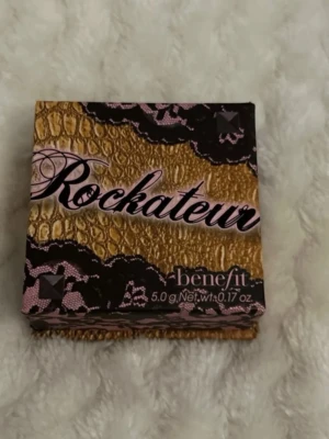 Benefit Rockateur Rouge 5g - Snyggt rouge från Benefit i nyansen Rockateur. Kommer i en lyxig guld- och svartmönstrad ask med rosa detaljer. Pudret ger en rosig, skimrande finish och är perfekt för att skapa en fräsch glow. Innehåller 5 gram.