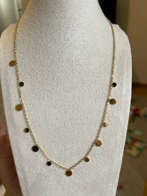 Guldigt halsband med små cirklar, vattentålig, rostfritt stål - Snyggt och minimalistiskt halsband i guldfärgad metall med små, blanka cirkelformade hängen längs hela kedjan. Perfekt för dig som gillar stilrena accessoarer med en modern touch. Kedjan är tunn och smidig, vilket gör halsbandet lätt att bära till olika outfits.
