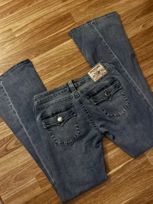 True Religion bootcut jeans blå - Säljer ett par blå bootcut jeans från True Religion med ikoniska kontrastsömmar och snygga fickdetaljer bak. Dom har blivit använda max 3 gånger men det finns inga täcken på användning, säljer då dom tyvärr aldrig kommer till användning. Priset kan diskuteras vid snabbt köp🩷