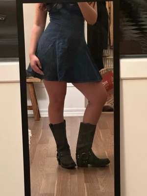 Svarta cowboy boots med spännen - Säljer ett par svarta cowboy boots i matt läder med coola metallspännen och dekorativa nitar runt ankeln. Bootsens höga skaft har dragflikar upptill. Pris kan diskuteras 