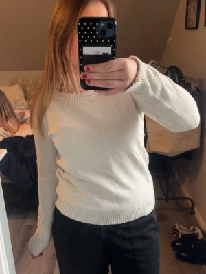 Vit stickad tröja med rund hals - Klassisk vit stickad tröja med rund halsringning och långa ärmar. Tröjan har ribbade muddar vid ärmslut och nederkant, vilket ger en snygg och enkel look. Perfekt att matcha med både jeans och kjol för en clean stil. Lite nopprig