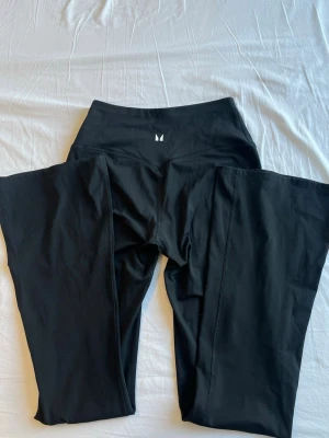 Svarta leggings från Myprotein - Snygga svarta leggings från Aim'n med hög midja och diskret logga framtill. Tillverkade i stretchigt och mjukt material som sitter skönt på kroppen. Perfekta för träning eller chill. Klassisk passform och stilren design.