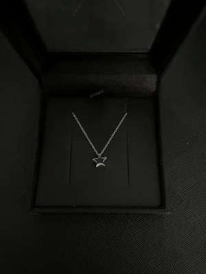 Silverhalsband med stjärnhänge - Snyggt halsband i silverfärgad metall med en enkel kedja och ett stjärnformat hänge i mycket bra skick. Perfekt accessoar för att lyfta din outfit med en stilren detalj. 