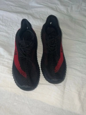 Svarta och röda sneakers Sport 550 - Snygga sneakers i svart med röda detaljer och texten 'SPORT 550' på sidan. Skorna har en stickad ovandel och tjock, räfflad sula för extra komfort. Perfekta för dig som gillar streetstyle och vill sticka ut med färg. Klassisk snörning och låg modell.