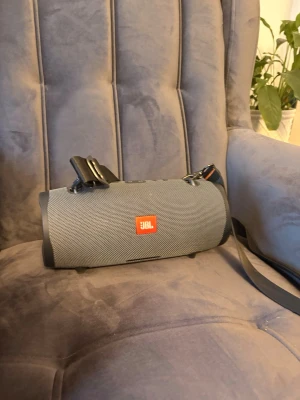 JBL Xtreme 2 grå brandad högtalare - Säljer en JBL Xtreme 2 bärbar högtalare i grått tygmaterial med robust cylinderformad design. Högtalaren har en axelrem för enkel transport och tydlig JBL-log sop framsidan. Perfekt för att ta med sig musiken överallt.
