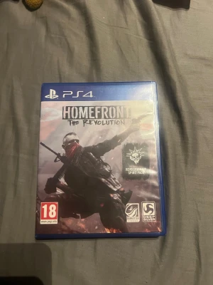 Homefront: The Revolution PS4 spel - Homefront: The Revolution till PS4 är ett actionfyllt FPS-spel där du kämpar mot en ockuperande makt i ett dystopiskt USA. Spelet kommer i ett blått plastfodral med omslagsbild på en rebell med röd scarf och gevär. Innehåller Revolutionär Spirit Pack.
