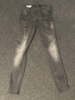Grå Anbass jeans från Replay - Snygga grå slim fit jeans från Replay med slitna detaljer. Jeansen har klassisk femficksdesign och smal passform. Perfekta för dig som gillar en modern och avslappnad stil. Säljer dem då de är för små. W28 L32