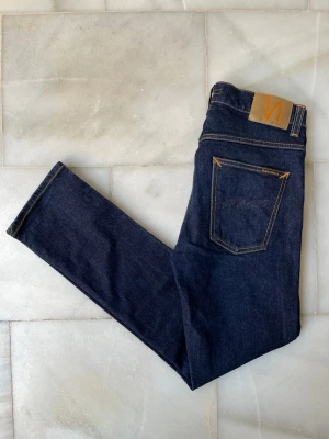 Mörkblå Nudie Jeans - Grim Tim - Mörkblå jeans från Nudie jeans i ett väldigt fint skick, modellen är Grim Tim😁                                  ——————————————————————————                                                          📐| Storlek: 32-32                                                   👖| Märke: Nudie Jeans                                         🔎 | Skick: Mycket fint!                                              💵 | Ny Pris: 1699kr                                                 ✍🏻 | Skriv om du har några frågor 