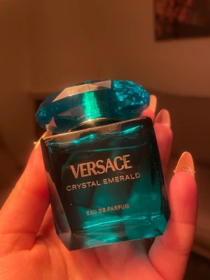 Versace Crystal Emerald Eau de Parfum 30ml - Versace Crystal Emerald Eau de Parfum i en lyxig smaragdgrön glasflaska med facettslipat lock. Flaskan har en elegant och modern design med guldtext. Perfekt för dig som gillar exklusiva dofter och snygga flaskor i badrumshyllan.