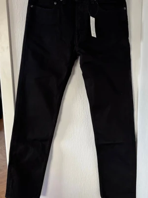 Svarta raka jeans - Säljer ett par svarta jeans med rak passform och klassisk femficksdesign. Jeansen har normal midja och stängs med dragkedja och knapp. Perfekta till en avslappnad streetwear-look. Storlek 31x32