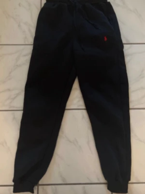 Svarta Polo Ralph Lauren byxor  - Säljer ett par svarta mjukis byxor från Polo Ralph Lauren.  Byxorna har resår i midjan och vid benslut samt samma röda logga. Mjukt och bekvämt material. Byxorna är i storlek S men kan användas som XS också. 