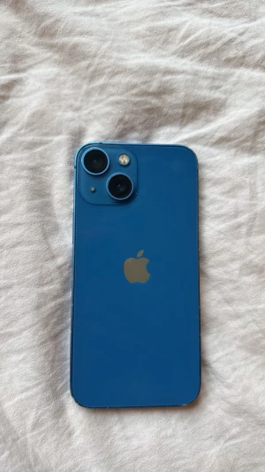 Blå iPhone med dubbla kameror - Snygg blå iPhone med stilren design och rundade hörn. Baksidan har två kameror och Apple-loggan i silver. Mobilen är lite skråmig men annors helt perfekt👌🏻
