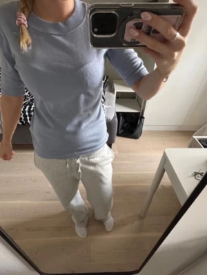 Ljusblå stickad topp med kort ärm - Säljer en ljusblå stickad topp med kort ärm och rund hals. Toppen har en ribbad kant vid halsen och är i en mjuk, bekväm kvalitet. Perfekt till jeans eller kjol för en enkel och snygg look.