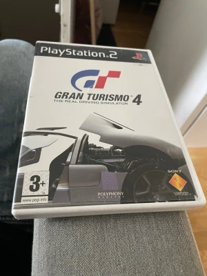Gran Turismo 4 till PlayStation 2 - Gran Turismo 4 till PlayStation 2, ett klassiskt racingspel från Polyphony Digital. Spelet kommer i originalfodral med omslag och skiva. Omslaget är vitt med en sportbil och spelets logga i blått och rött. Perfekt för dig som gillar realistiska bilspel och samlar på PS2-spel.