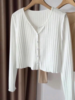 Vit ribbad cropped cardigan - Packad och redo att skickas! Säljer en vit ribbad cardigan med knappar framtill och lång ärm. Tröjan är croppad och har en smickrande V-ringning. Tillverkad i ett mjukt, stretchigt material som sitter snyggt på kroppen. Perfekt att styla med höga jeans eller kjol.