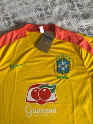 Brasilien fotbollströja och shorts Nike - Brasil fotbollsset i storlek M. Shortsen har fickor med dragkedjor. Helt nya och oanvända, perfekt till sommaren. Hör gärna av vid frågor!