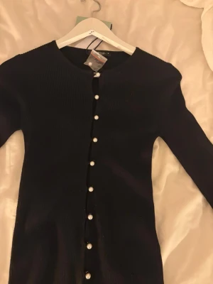 Svart topp - Svart topp med pärl deltaljer, aldrig använd, extra knapp finns med 