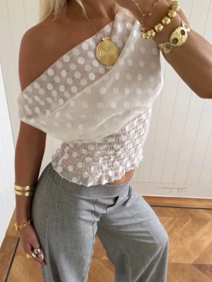 Vit prickig off shoulder topp - Trendig vit off shoulder topp från Designbysi med stora prickar i mesh-tyg. Toppen har smockad midja som ger en snygg siluett. Perfekt för dig som vill sticka ut med en unik och luftig look. Storleken är i xs/s och är använd endast en gång! 💕Pris går att diskuteras :)