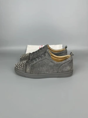 CHRISTIAN LOUBOUTIN LOUIS JUNIOR SPIKES SNEAKER GREY - • The shoes have been gently used and are in very good condition  • Size: 43.5 (fits 44–44.5)  • Color: Grey   • Retail price: 9500 SEK / 795€  • Dustbag included