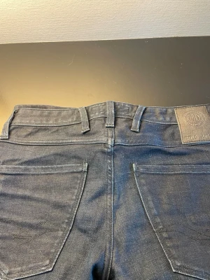 Mörkblå jeans från Replay - Snygga mörkblå jeans från Replay med klassisk femficksmodell och raka ben. Jeansen har bälteshällor, knappgylf och detaljerade sömmar. Materialet är denim med en mjuk känsla och lätt stretch för extra komfort.