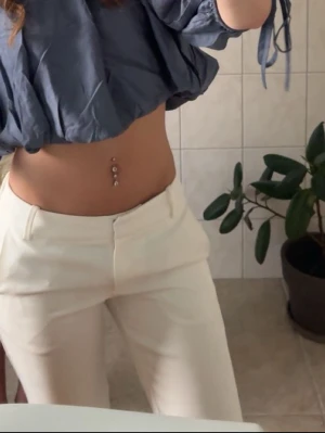Vita kostymbyxor med rak passform - Snygga vita kostymbyxor med rak passform och hög midja. Byxorna har klassiska fickor och stängs med dragkedja och hake. Perfekta för en clean och stilren look. Materialet ser ut att vara mjukt och följsamt, troligen polyesterblandning.