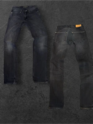 Acne Jeans i straight fit - Säljer ett par mörkblå jeans från Acne Jeans med raka ben och klassisk femficksmodell. Jeansen har snygga slitningar och kontrastsömmar samt en läderpatch med logga bak i midjan. Perfekta för en stilren och avslappnad look.