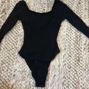 Svart ribbad långärmad bodysuit - Svart ribbad bodysuit med lång ärm från H&M divided.  Kroppsnära passform. Storlek XS