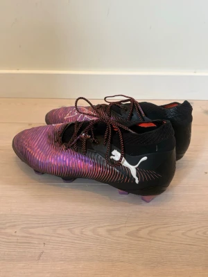 Puma Future 8 Ultimate FG Unlimeted  - Säljer ett par Puma Future fotbollsskor i lila och svart med vita detaljer och snörning. Använda ett fåtal gånger och kommer med en påse till (se bilderna). Nypris: 2699 kr. 