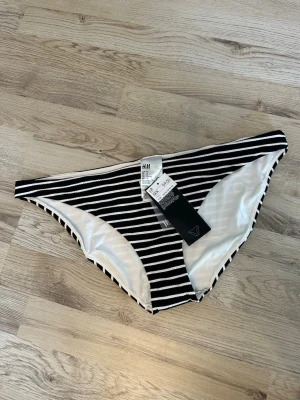Svartvita randiga trosor från H&M - Svartvita trosor från H&M med horisontella ränder. Klassisk bikini-modell med vit insida och stretchigt material. Perfekta för dig som gillar enkel och stilren design.