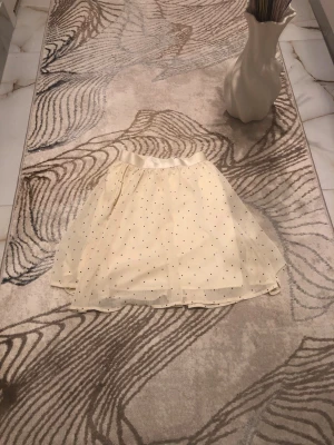 Ljusgul prickig kortkjol i tyll - Söt ljusgul kortkjol i tyll med små svarta prickar för barn. Kjolen har ett tunt, transparent lager ovanpå och ett mjukt innerfoder. Resår i midjan för bekväm passform. Perfekt för dig som gillar en lekfull och trendig stil. Använd endast ett fåtal gånger. Är öppen med prisförslag😊