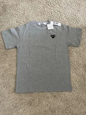 Grå t-shirt från Comme des Garçons Play - Snygg grå t-shirt från Comme des Garçons. Storlek M.