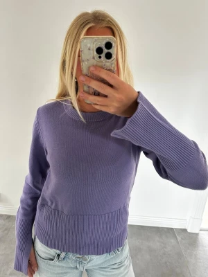 BikBok Ljuslila stickad tröja med vida ärmar - Ljuslila stickad tröja med rund hals och långa, vida ärmar med en slits. Tröjan har ribbstickade detaljer vid ärmslut och nederkant som ger en snygg kontrast. Endast använd 1 gång så den är som helt ny! Storlek S.