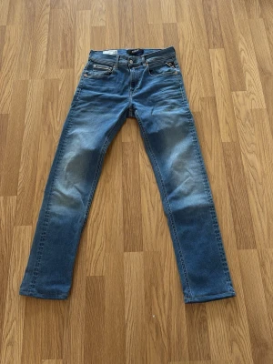 Blå straight fit jeans Grover - Bara provade 1 gång. Helt nya!Snygga blå jeans från Grover i straight fit-modell. Klassisk femficksdesign med ljusa slitningar på låren och knäna för en trendig look. Tillverkade i denim med detaljer i kopparfärgade nitar och kontrastsömmar.