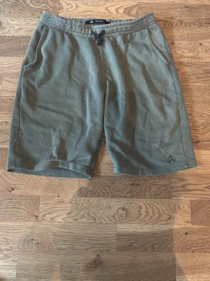 Olivgröna mjukis/idrotts shorts - Olivgröna shorts från  i mjukt material. De har snörning i midjan, två sidofickor.