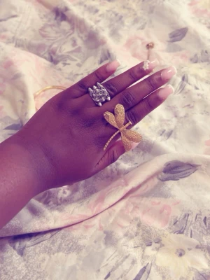 Guldigt armband med vita pärlor - Säljer ett elegant armband i guldfärgad metall med vita pärlor i fyrklöverform. Armbandet har en tunn kedja och justerbar längd. Perfekt för dig som gillar stilrena accessoarer med en touch av lyx.