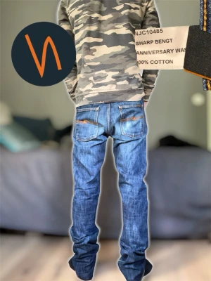 Nudie Jeans Discontinued - Säljer ett par klassiska blå jeans från Nudie Jeans, modell Sharp Bengt Anniversary Wash. Jeansen har raka ben, fem fickor och snygga slitningar på bakfickorna. Tillverkade i 100% bomull för en skön och hållbar känsla.