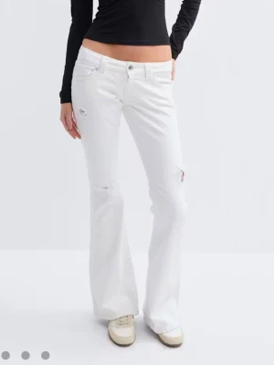 Vita bootcut jeans med slitningar - Säljer ett par vita bootcut jeans med låg midja och slitningar vid knäna. Jeansen har klassisk femficksmodell och stängs med knapp och dragkedja. Perfekta för dig som gillar en avslappnad och trendig look.
