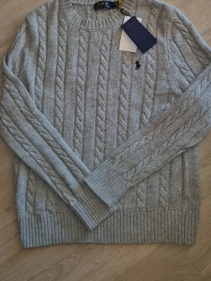 Ralph Lauren tröja - Fin kabelstickad tröja från Ralph Lauren i färgen grå, helt ny! Storlek S. Hör av er vid frågor eller funderingar! 