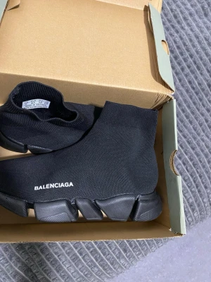  Speed Trainer svarta sneakers - Svarta  Speed Trainer sneakers med stickad ovandel i textil och chunky sula. Strumpliknande passform och vit logga på sidan ger en clean och modern look. Perfekta för dig som gillar streetwear och vill ha något som sticker ut.