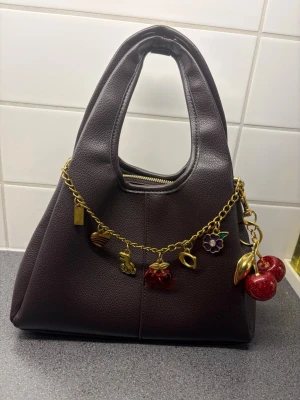 Väska c*ach - Super fin & trendig väska i en röd/brun färg. Helt ny. Allt på bilden ingår både väska o bag charms!