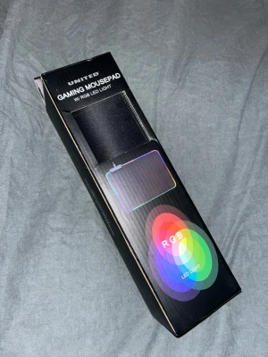 Musmatta RGB LED - Gaming musmatta från United med RGB LED-belysning. Svart rektangulär design med färgade ljuseffekter runt kanterna. Perfekt för gaming setup och ger snygg belysning till skrivbordet. Kommer i originalförpackning och är helt ny och oanvänd.