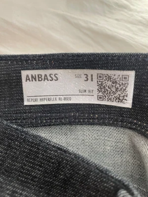 Replay Anbass Slim Fit jeans blå - Säljer ett par svarta Replay Anbass jeans i modellen Slim Fit. Jeansen har klassisk femficksdesign, kontrastsömmar och Replay Hyperflex-material för extra stretch och komfort. Snygga detaljer på bakfickorna och läderpatch i midjan.
