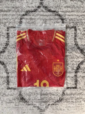 Spanien adidas tröja - Säljer en Spanien adidas tröja med lamine yamal på ryggen, tröjan är storlek M och dustbag kommer med! Tröjan är i helt nytt skick då den är använd max 3 gånger! Kom gärna med funderingar eller frågor.